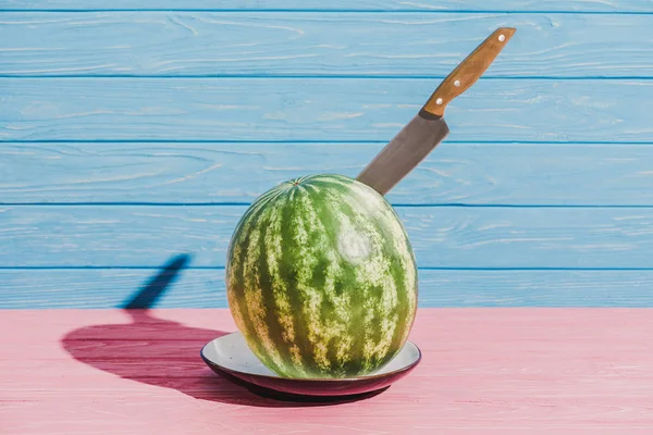 Vista de perto da melancia fresca com faca na placa no fundo azul — Fotografia de Stock