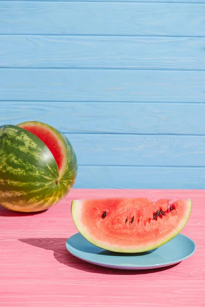 Nahaufnahme von frischer Wassermelone auf rosa Tischplatte vor blauem Hintergrund — Stockfoto