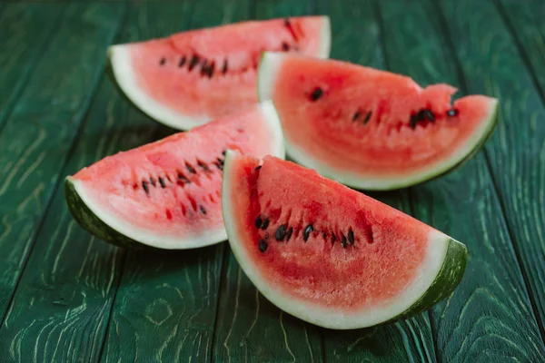 Nahaufnahme von Wassermelonenscheiben auf grüner Holzoberfläche — Stockfoto