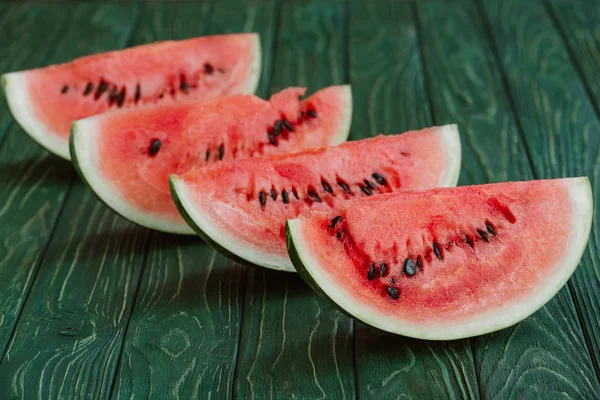 Nahaufnahme von Wassermelonenscheiben auf grüner Holzoberfläche — Stockfoto