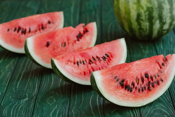 Nahaufnahme von Wassermelonenscheiben auf grüner Holzoberfläche — Stockfoto