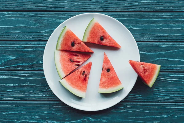 Draufsicht der Anordnung von Saft-Wassermelonenstücken auf Teller auf blauer Holztischplatte — Stockfoto