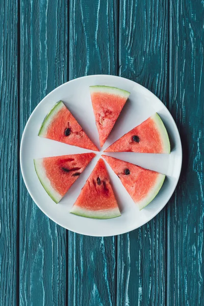 Top view of arrangement of juice watermelon pieces on plate on blue wooden tabletop — Stock Photo