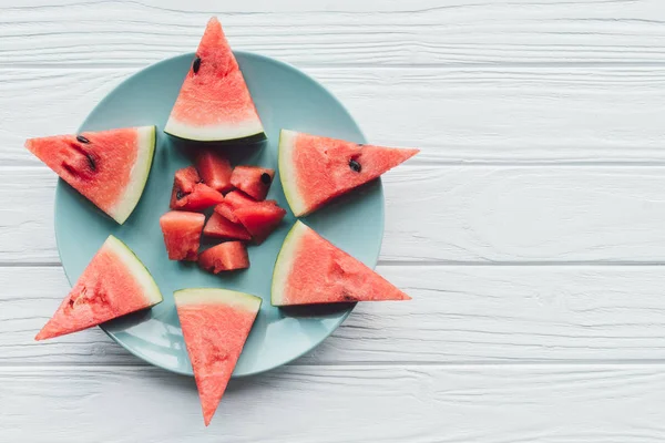 Draufsicht auf frische Wassermelonenstücke auf Teller auf weißer Holzoberfläche — Stockfoto