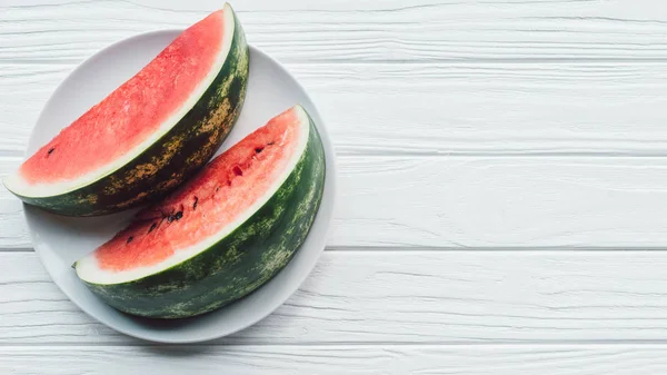 Draufsicht auf Saft-Wassermelonen-Stücke auf Teller auf weißer Holzoberfläche — Stockfoto