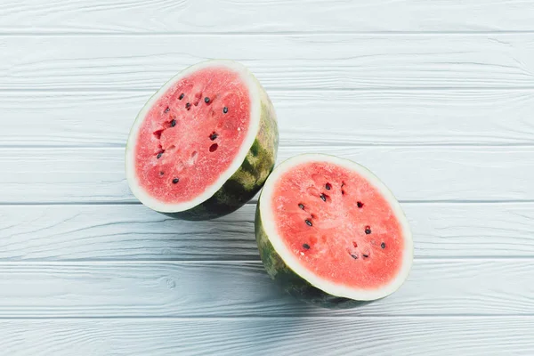 Draufsicht auf frische Wassermelonenhälften auf weißer Holzoberfläche — Stockfoto