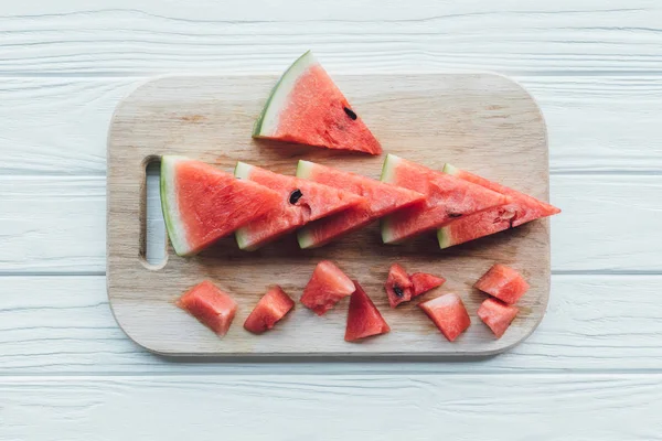 Flat lay with arranged watermelon pieces on cutting board on wooden tabletop — Stock Photo