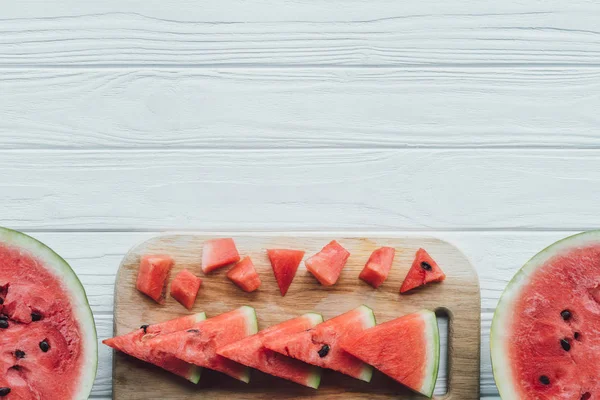 Flat lay with arranged watermelon pieces on cutting board on wooden tabletop — Stock Photo