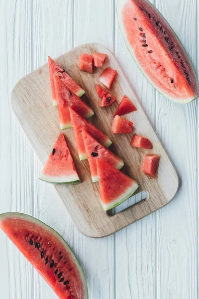 Flat lay with arranged watermelon pieces on cutting board on wooden tabletop — Stock Photo