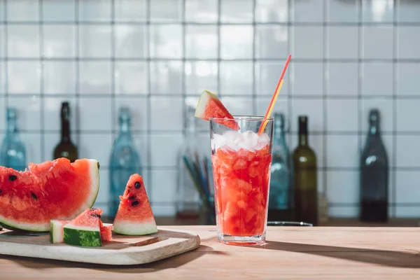 Close up view of watermelon drink in glass and pieces of fresh watermelon on cutting board in cafe — Stock Photo