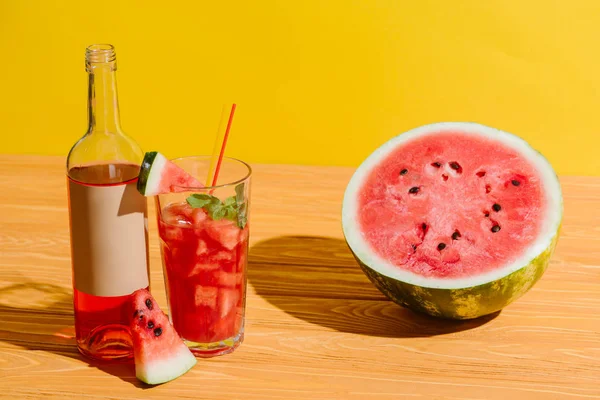 Close up view of fresh watermelon and watermelon drink on wooden surface on yellow background — Stock Photo