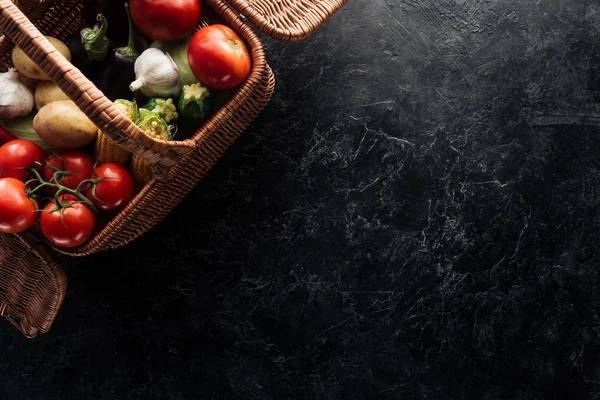 Flat lay with various fresh vegetables in basket on black marble tabletop — Stock Photo