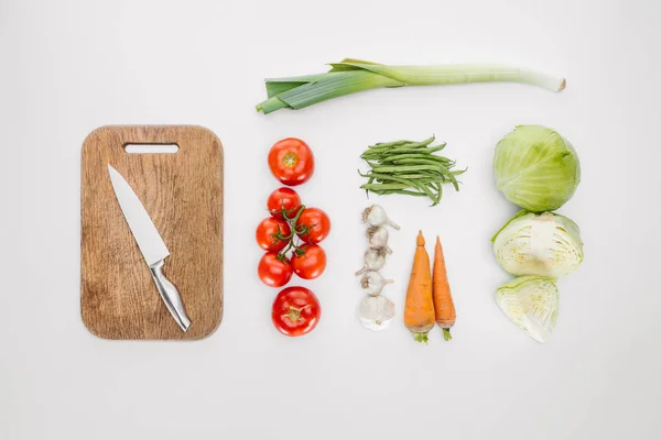 Vista superior de vegetais maduros e tábua de corte com faca isolada em branco — Fotografia de Stock