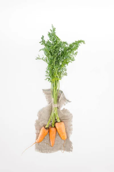 Top view of fresh carrots tied with rope on sackcloth isolated on white — Stock Photo