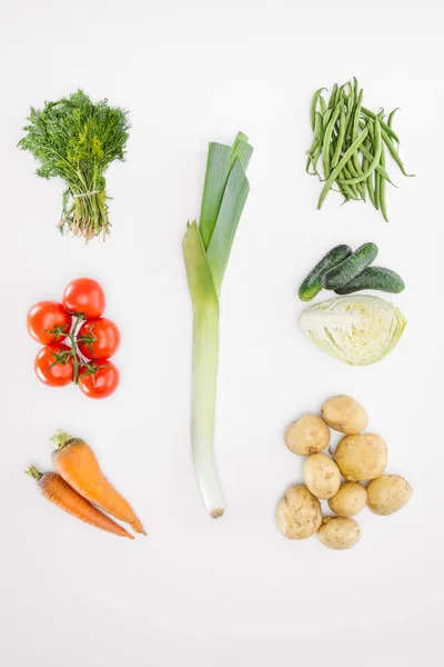 Плоский слой с различными спелыми овощами с луком-пореем посередине, изолированными на белом — стоковое фото