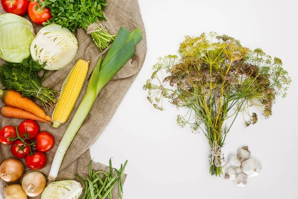 Food composition with fresh vegetables arranged on sackcloth isolated on white — Stock Photo