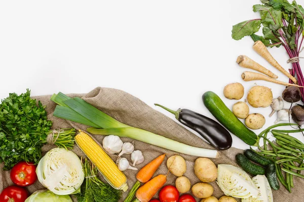 Composizione alimentare con verdure fresche disposte su sacco isolato su bianco — Foto stock