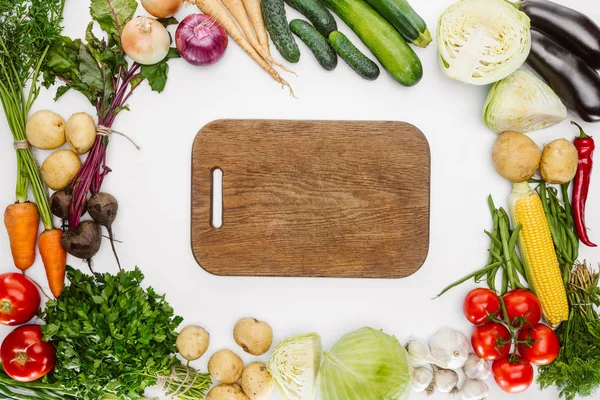 Plat posé avec des légumes d'automne mûrs et planche à découper en bois vide isolé sur blanc — Photo de stock