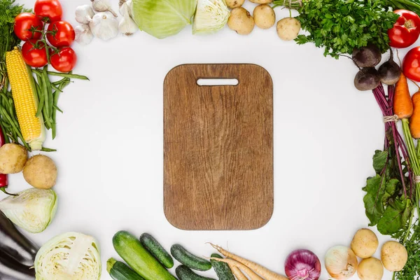 Tendido plano con verduras maduras de otoño y tabla de cortar de madera vacía aislada en blanco - foto de stock