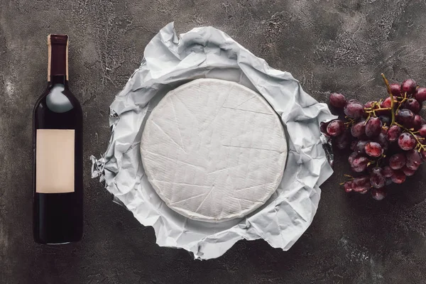 Vista dall'alto di bottiglia di vino, brie e uva su superficie scura — Foto stock