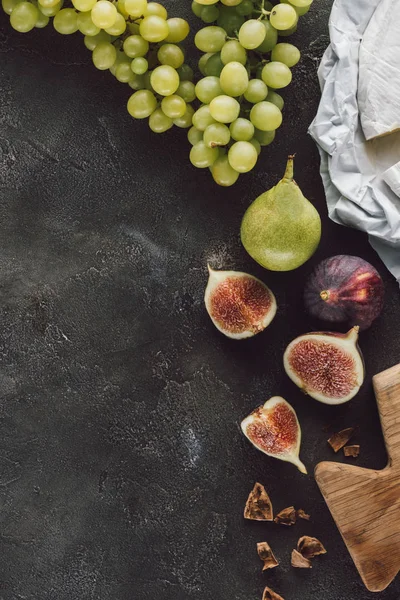 Pose plate avec figues disposées, raisin et fromage sur une surface sombre — Photo de stock