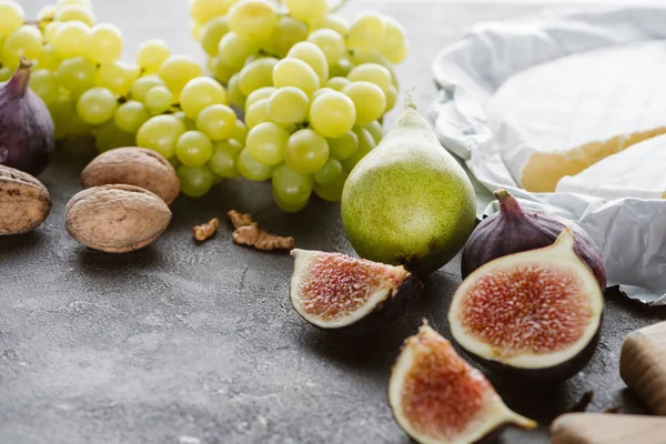 Vista ravvicinata di fichi, formaggio camembert, uva e pera disposti su tavolo — Foto stock