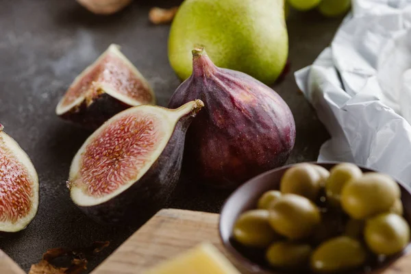 Close up view of figs, olives in bowl and pear arranged on tabletop — Stock Photo