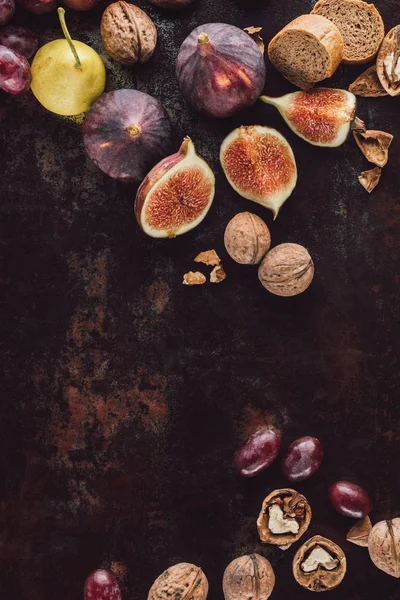 Food composition with assorted bread, fruits and hazelnuts on dark surface — Stock Photo