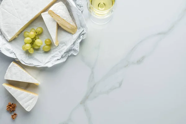 Flat lay com copo de vinho, queijo camembert e uva na superfície de mármore branco — Fotografia de Stock