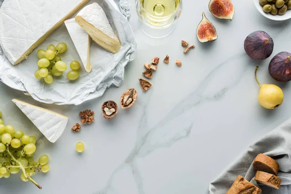 Plat avec fromage, vin et fruits disposés sur la surface de marbre blanc — Photo de stock