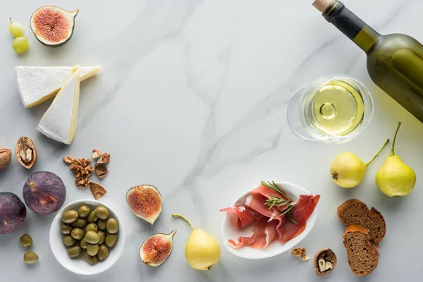 Flat lay com vinho, queijo brie, jamon e figos sortidos em mesa de mármore branco — Fotografia de Stock