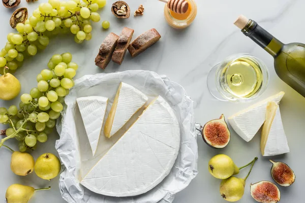 Essenszusammensetzung mit Brie-Käse, Wein, Trauben und Brot auf weißem Marmor — Stockfoto