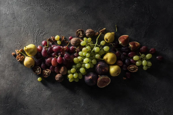 Flat lay with various fruits and hazelnuts arranged on dark surface — Stock Photo