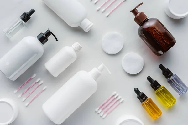 Flache Lage mit Cremeflaschen, natürlichen Ölen und Kosmetikkissen auf weißer Oberfläche, Schönheitskonzept — Stockfoto