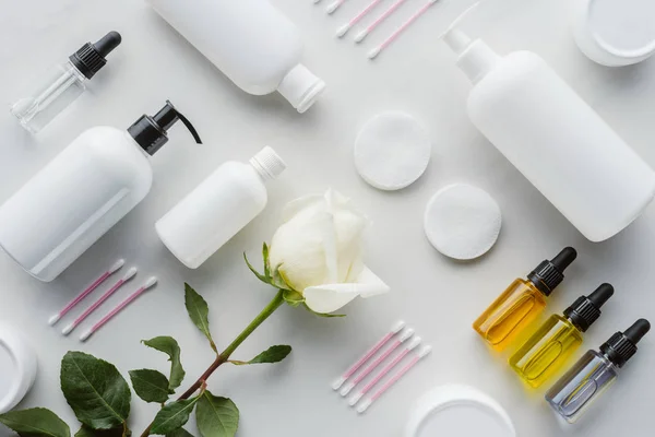 Flat lay with bottles of cream, natural oils and rose on white surface, beauty concept — Stock Photo
