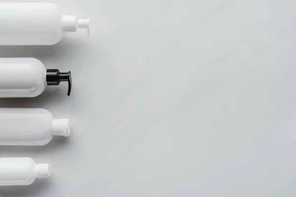 Top view of bottles of lotion on white surface, beauty concept — Stock Photo