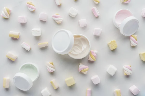 Vista superior de garrafas de creme e marshmallows na superfície branca, conceito de beleza — Fotografia de Stock