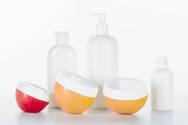 Bouteilles de crème rouge, orange et blanche sur surface blanche, concept beauté — Photo de stock