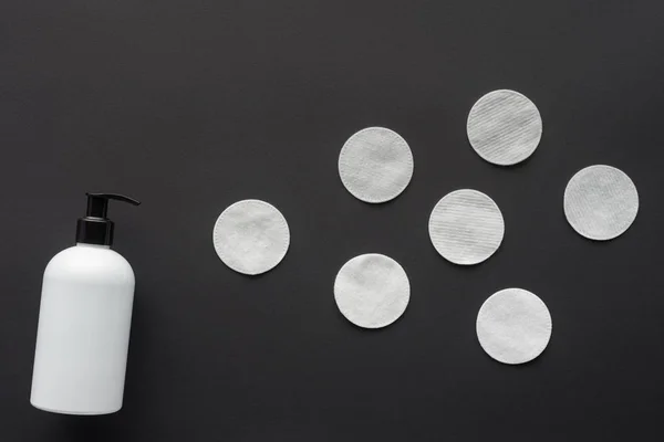 Vista superior de la botella de loción y almohadillas cosméticas aisladas en negro, concepto de belleza - foto de stock