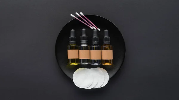 Top view of bottles of natural oils and cosmetic pads on plate, beauty concept — Stock Photo