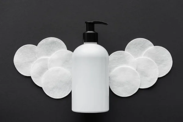 Vista superior de la botella de crema y almohadillas cosméticas aisladas en negro, concepto de belleza - foto de stock