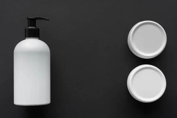 Top view of bottles of lotion and cream isolated on black, beauty concept — Stock Photo