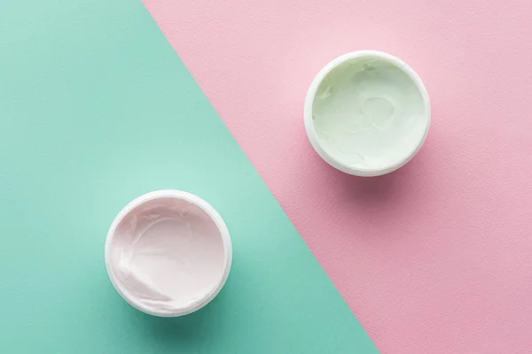 Vue du dessus des bouteilles de crème sur surface rose et verte, concept beauté — Photo de stock