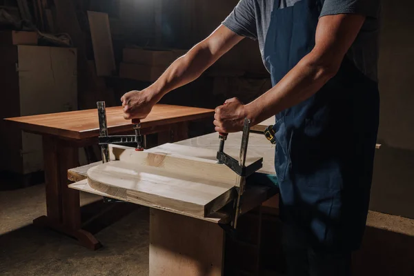 Tiro cortado de carpintero en delantal trabajando en madera en el taller - foto de stock