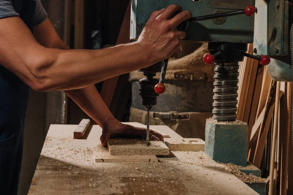 Teilansicht eines Holzarbeiters mit Elektrobohrmaschine auf Holz in der Werkstatt — Stockfoto