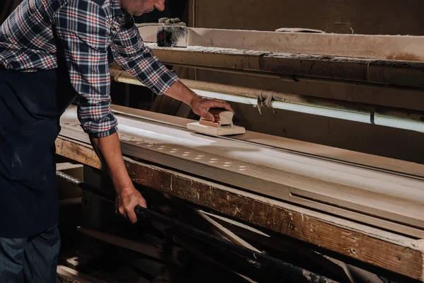 Cropped shot of woodworker planing wood with hand plane at workshop — Stock Photo