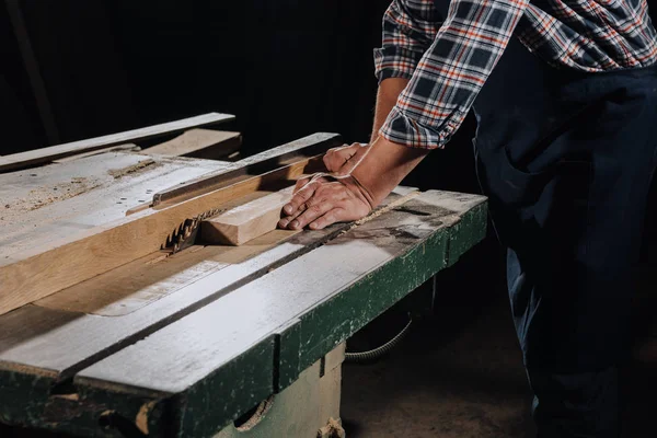 Partial view of carpenter using saw at wooden workshop — Stock Photo