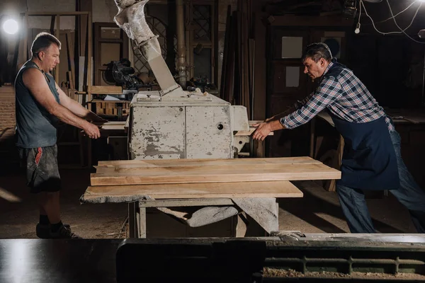 Carpenters working with wooden planks at wooden workshop — Stock Photo