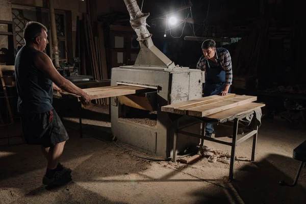 Carpinteros trabajando con tablones de madera en taller de madera - foto de stock