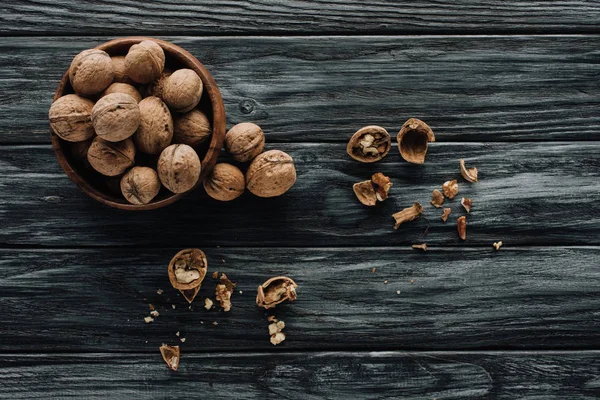 Organic walnuts in wooden bowl on dark wooden table — Stock Photo